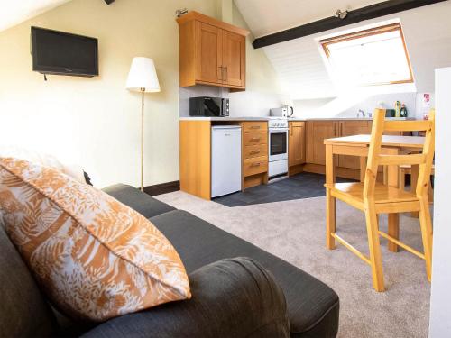 a living room with a couch and a table and a kitchen at Alder Cottage - Uk46154 in Farlam