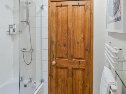 Pitmans Cottage في ريتون: باب خشبي في حمام مع دش