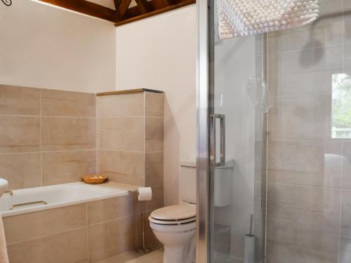 y baño con bañera, aseo y ducha. en Byre Cottage - Meadowbrook Farm, en Thame