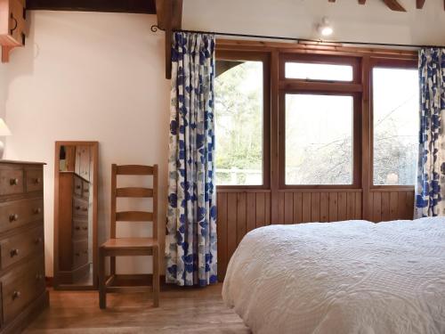 um quarto com uma cama, uma cadeira e uma janela em Byre Cottage - Meadowbrook Farm em Thame