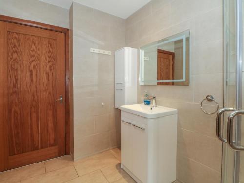ein Bad mit einem Waschbecken, einem Spiegel und einer Dusche in der Unterkunft The Brambles in Wrexham