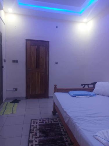 Cette chambre comprend deux lits et une porte avec une lumière bleue. dans l'établissement Castor, à Ziguinchor