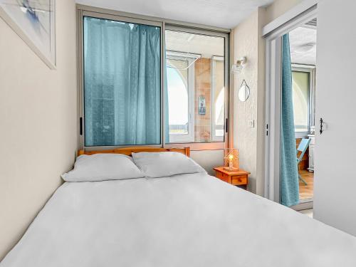 a white bed in a room with a large window at Charme Marin à Leucate in Leucate