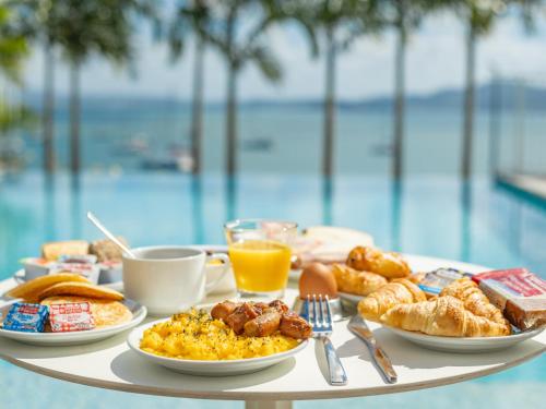 a breakfast table with breakfast foods on a table near a pool at B&B HOTEL Fort-de-France in Fort-de-France