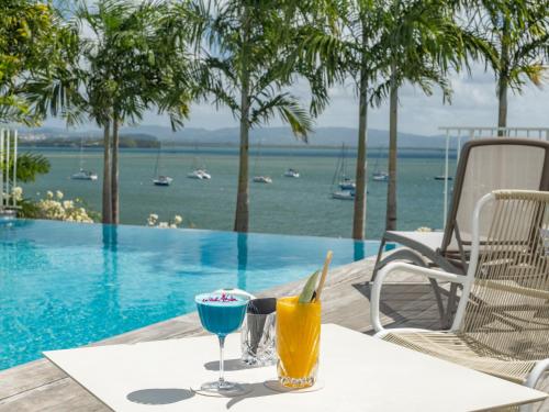 a table with a drink on it next to a pool at B&B HOTEL Fort-de-France in Fort-de-France