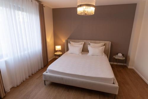 - une chambre dotée d'un grand lit avec des draps et des oreillers blancs dans l'établissement Splendide villa proche de Colmar, à Bischwihr