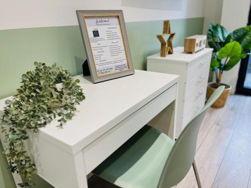 a white desk with a sign and a chair at Delightful Ealing Retreat - Steps to Tube & Shops in Ealing