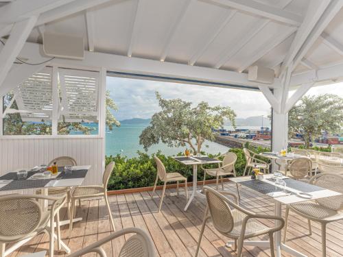 a patio with tables and chairs and a view of the ocean at B&B HOTEL Fort-de-France in Fort-de-France
