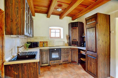 una cocina con armarios de madera y fregadero en Zuzmó Guesthouse, Jósvafő, Aggtelek National Park - Stylish 150 year old farmhouse for 10 guests, en Jósvafő
