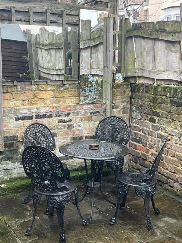 a table and four chairs sitting next to a brick wall at Beautiful Traditional English 4 bedroom home in Greenwich in Plumstead