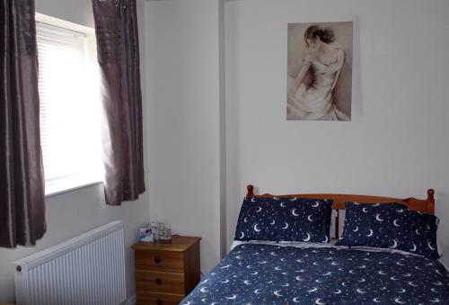 Un dormitorio con una cama y una foto de una mujer en Cosy room with 3 bed spaces in a friendly bungalow en Bletchley