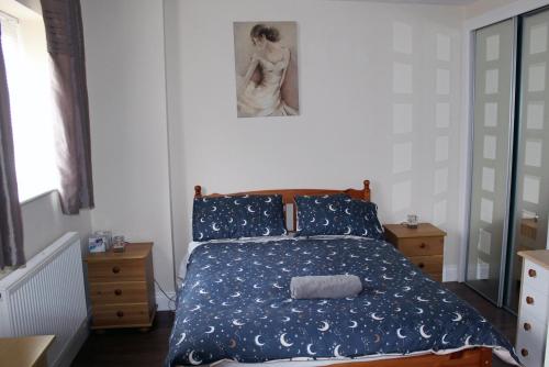a bedroom with a bed with a blue comforter at Cosy room with 3 bed spaces in a friendly bungalow in Bletchley
