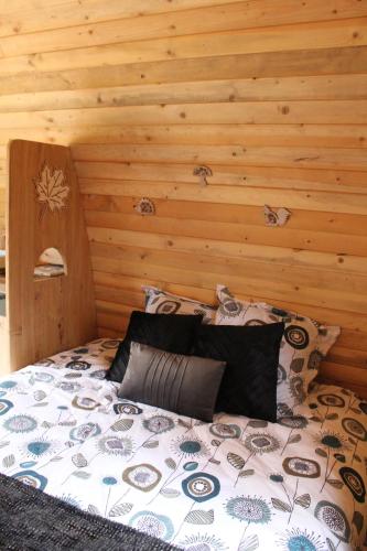 L'ERABLE - CABANE INSOLITE et COCOONING 2 personnes - CAMPING LE BEL AIR في Limogne-en-Quercy: سرير في غرفة ذات جدار خشبي