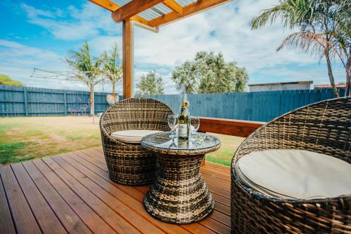 two wicker chairs and a table on a deck at Sunrise Accommodation in Whakatane