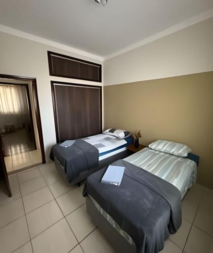 a hotel room with two beds and a window at Apartamento no Centro! in Franca