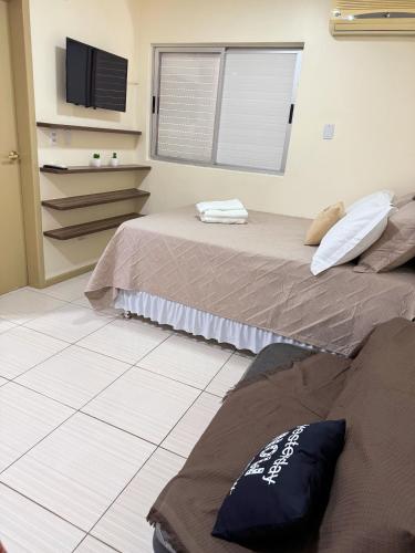 um quarto com duas camas e uma televisão na parede em Studio25_Apto região central Foz em Foz do Iguaçu