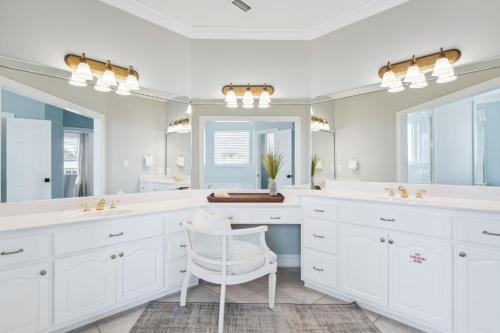a white bathroom with two sinks and a chair at Dock n Dune in Seagrove Beach