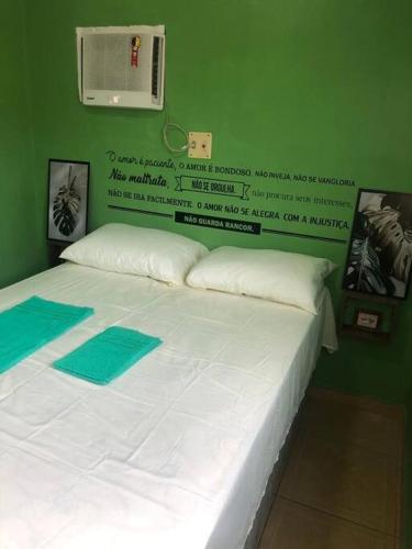 a bedroom with a white bed with a green wall at Apartamento Natureza Verde Manauara in Manaus
