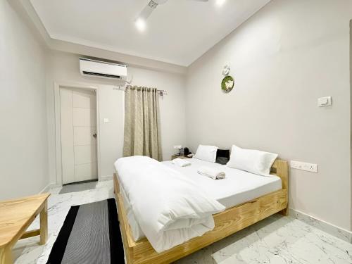 1 dormitorio con 1 cama grande con sábanas blancas en Stay Inn Kaashvi (A unit of Admire India Tourism Pvt. Ltd.) en Varanasi