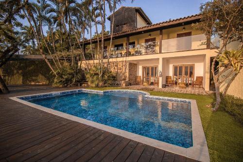 a swimming pool in front of a house at suites vista pro mar ilhabela in Ilhabela