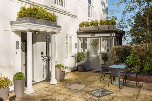 a white house with a patio with a table and chairs at Fabulous ground floor apartment. in Great Malvern