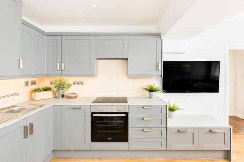 a white kitchen with white cabinets and a sink at Fabulous ground floor apartment. in Great Malvern