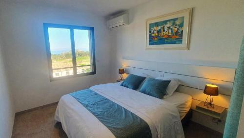 a bedroom with a bed and a window at Villa avec piscine et vue mer à Lozari in Palasca