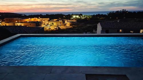 a swimming pool with a view of a city at night at Villa avec piscine et vue mer à Lozari in Palasca