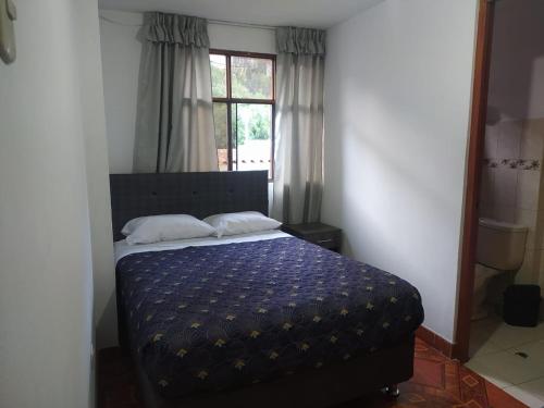 una camera da letto con un letto con un piumone blu e una finestra di HOSPEDAJE EL ARCO ad Ayacucho