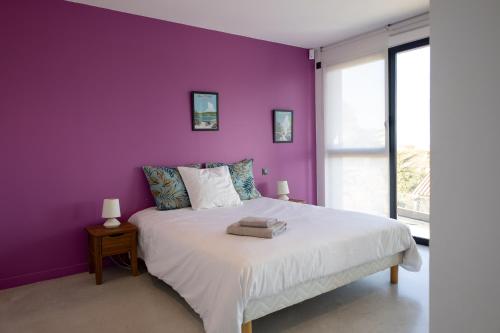 a bedroom with a purple wall and a bed at Les Mille et une Vitres in Port-Vendres