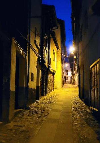 an empty alley way at night with a street light at Casa Cofrades in Hervás