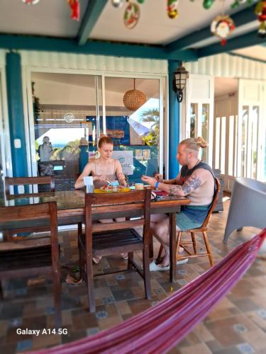 a man and a woman sitting at a table at Hostel SaltWater in San Juan del Sur