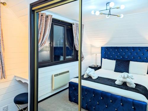 1 dormitorio con cama azul y espejo en Danu 1A -Hot Tub-Perth-Pet Friendly-Luxury-Romantic, en Perth