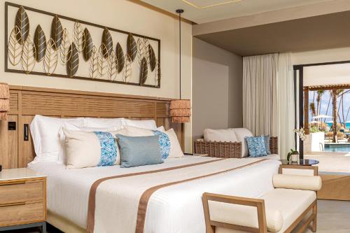 a bedroom with a large bed and a chair at Secrets Tides Punta Cana - All Inclusive in Punta Cana