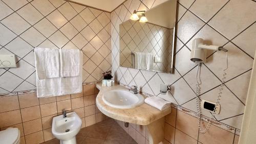 ein Badezimmer mit einem Waschbecken, einem WC und einem Spiegel in der Unterkunft La Perla Hotel in SantʼAnna Arresi