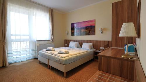 a bedroom with a bed and a desk and a television at Balaton Colors Beach Hotel in Siófok