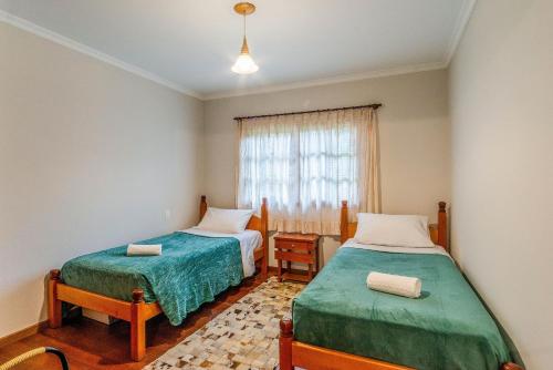 ein Schlafzimmer mit zwei Betten und einem Fenster in der Unterkunft Bela casa estilo chalé em Canela RCF160 in Canela