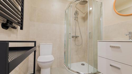 a bathroom with a toilet and a glass shower at VacationClub - Apartamenty Zakopiańskie Apartament 137 in Zakopane
