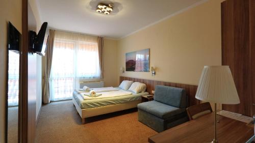 a bedroom with a bed and a chair and a lamp at Balaton Colors Beach Hotel in Siófok