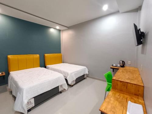 um quarto com duas camas e uma mesa e uma televisão em Grand Mulia Hotel Kisaran em Kisaran