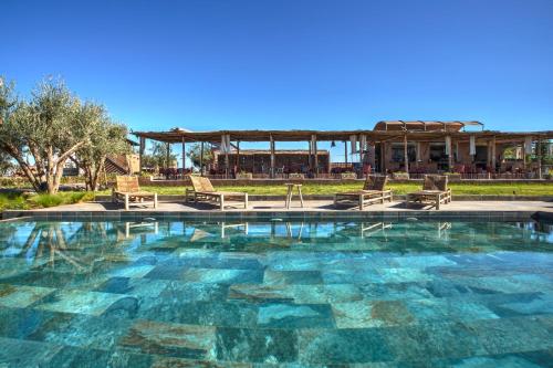 una gran piscina con sillas y cenador en The Ranch Resort en Marrakech