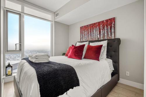 a bedroom with a large bed with red pillows at NEW! 34th FL High Rise, PRIME Location, Downtown Near Stampede & Saddledome, FREE Wine & More! in Calgary