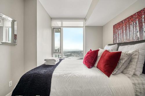 a bedroom with a large bed with red pillows at PRIME Downtown 34th FL - Near Stampede, Casino, Bars! FREE Banff Pass, Parking, Wine! in Calgary