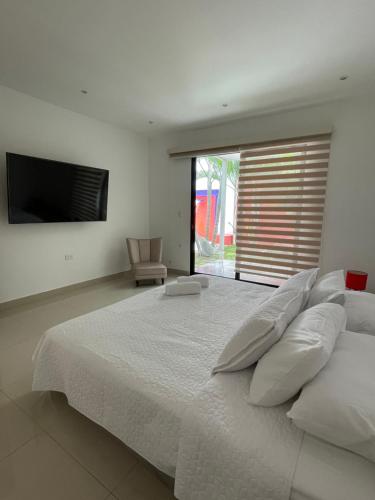 a bedroom with a large white bed with a television at Hotel Casa David in Rivera
