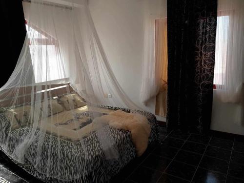 ein Schlafzimmer mit einem Bett mit einem Vorhang und einem Fenster in der Unterkunft Vivenda Na Baia das Gatas in Baia das Gatas