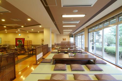 a restaurant with tables and chairs and windows at Route Inn Grantia Fukuoka Miyawaka - Wakita Onsen in Miyawaka