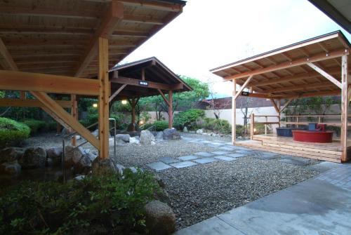 a wooden pavilion in a garden with rocks at Route Inn Grantia Fukuoka Miyawaka - Wakita Onsen in Miyawaka