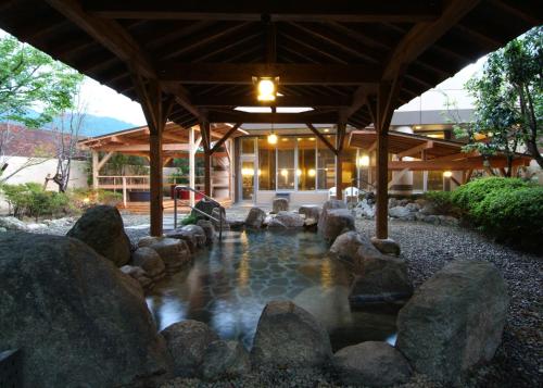a backyard with a pond with rocks and a building at Route Inn Grantia Fukuoka Miyawaka - Wakita Onsen in Miyawaka