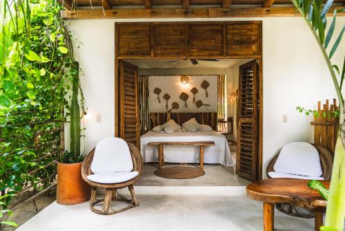 a bedroom in a villa with a bed and chairs at Casa Chula Hotel Boutique Frente al Mar in Tierra Blanca
