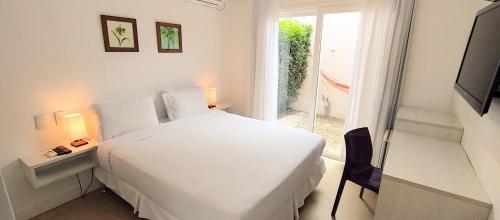 a white bedroom with a bed and a window at Parador Búzios Boutique Hotel in Búzios
